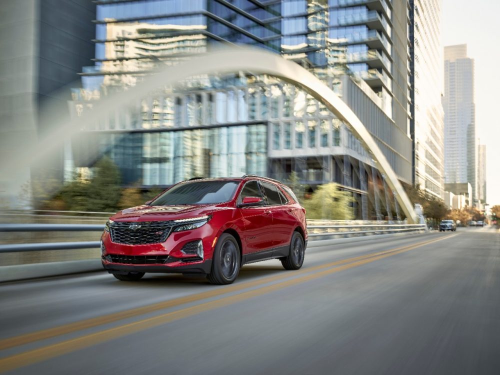 Red 2024 Chevrolet Equinox driving down a city street