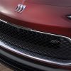 Close-up view of grille and badge of the 2024 Buick Encore GX Sport Touring in Cinnabar Metallic