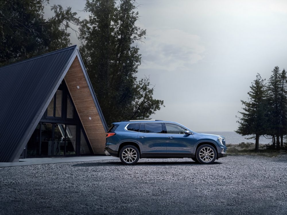 Side profile view of 2024 GMC Acadia Denali parked near A-frame building