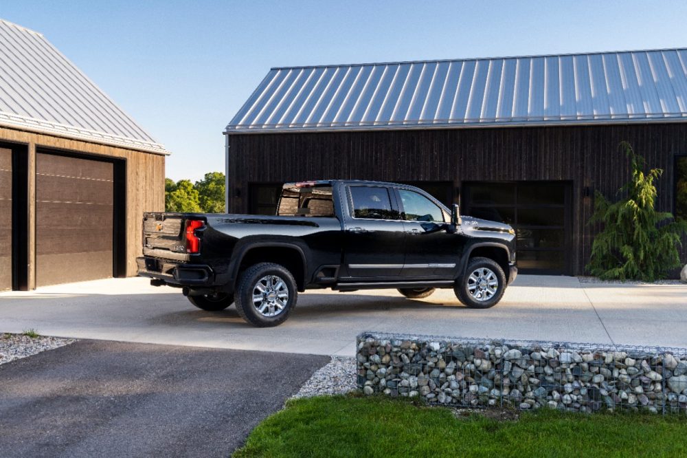 Rear side view of black 2024 Chevrolet Silverado HD High Country parked in front of buildings