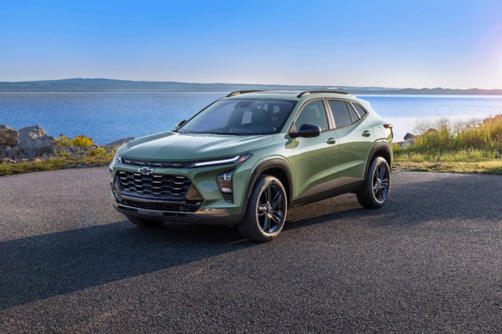 Front side view of green 2024 Chevrolet Trax ACTIV parked on road in front of lake