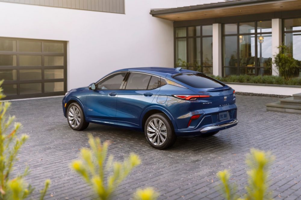 Rear side view of blue 2024 Buick Envista Avenir parked on brick surface in front of house