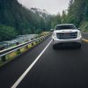 Front view of 2024 GMC Sierra 1500 SLT driving down road next to river in mountainous forest