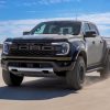 A 2024 Ford Ranger Raptor drivers through a stark desert against a clear blue sky