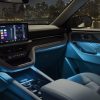 The dashboard and center console of a 2025 Ford Explorer Platinum with a Salt Crystal Gray interior and Blue ambient lighting