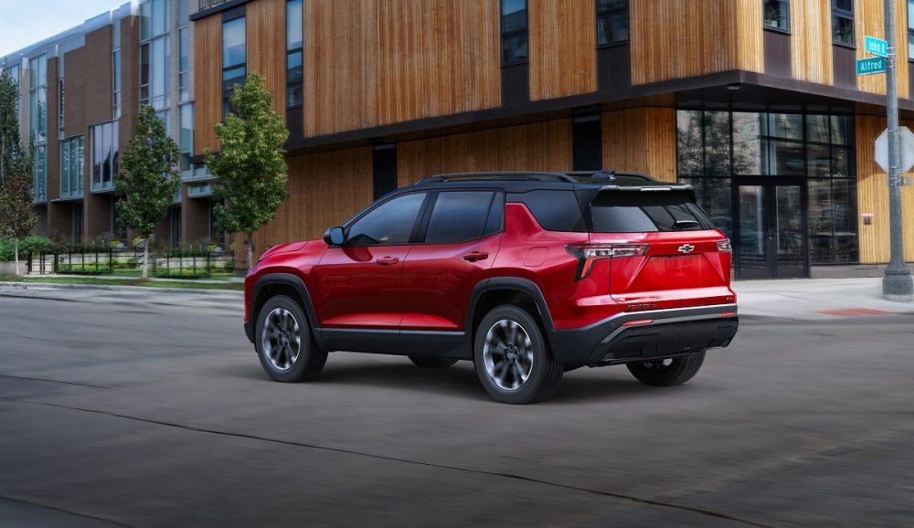 Rear 3/4 view of 2025 Chevrolet Equinox RS in Radiant Red Tintcoat driving on a road