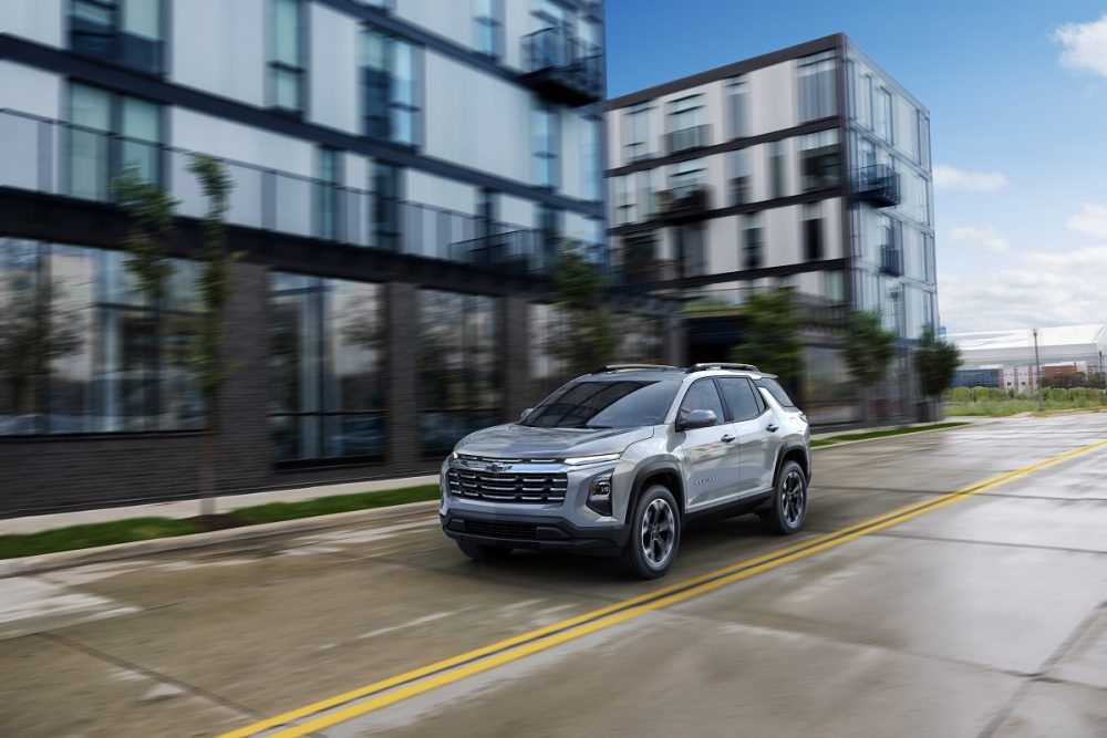 Front 3/4 view of a 2025 Chevrolet Equinox LT in Sterling Gray Metallic driving down a road