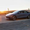 Side view of a gray 2024 Hyundai Ioniq 6 driving down a desert road as the setting sun reflects off the landscape