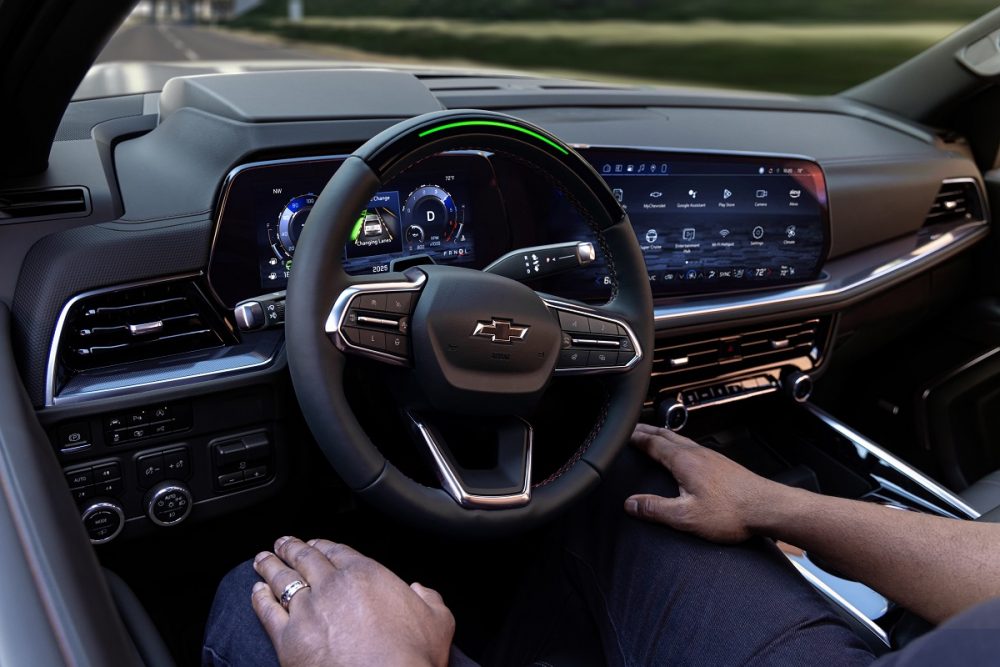 A green-lit steering wheel is shown as a person drives hands-free in the 2025 Chevrolet Tahoe RST