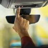 A person pushes the blue OnStar button inside a General Motors vehicle