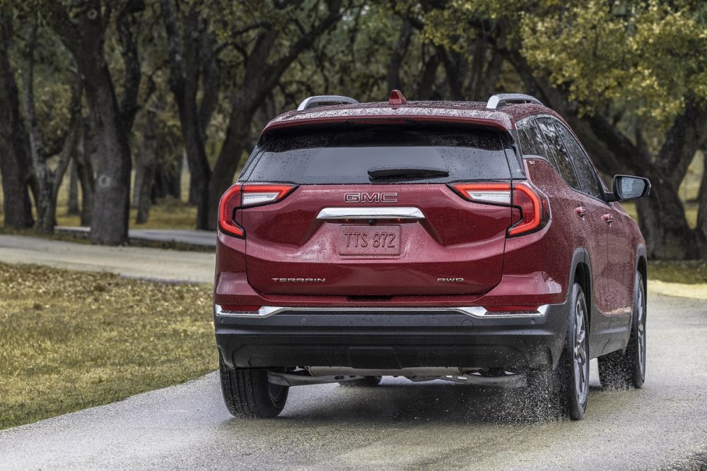 Rear view of red  GMC Terrain SLT driving on wet road