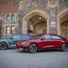 A green 2024 Hyundai Ioniq 5 and a red 2024 Hyundai Ioniq 6 are parked next to each other in front of an old stone building