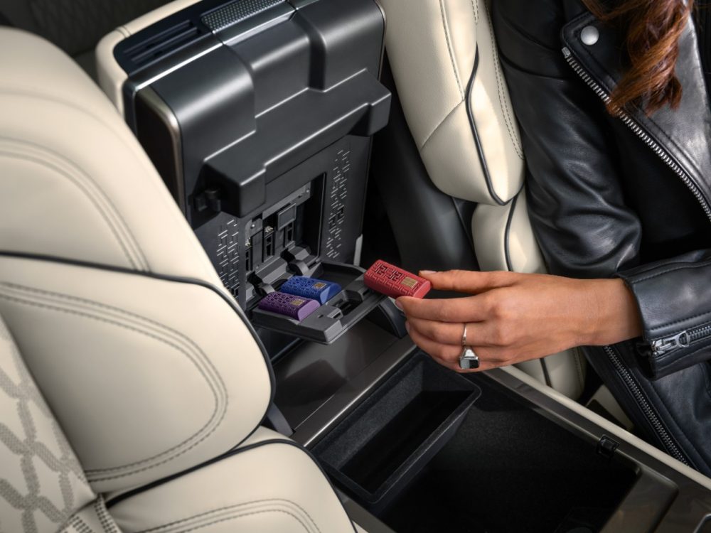 A human hand prepares to plug a Lincoln Digital Scent cartridge into the center console of a 2024 Lincoln Nautilus