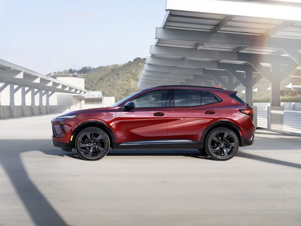 Side view of a red 2024 Buick Envision Sport Touring parked under a canopy