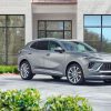 Front 3/4 view of a Moonstone Gray Metallic 2024 Buick Envision Avenir parked in front of a building