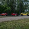 Side views of the 2024 Chevrolet Trax LT in Cayenne Orange Metallic, RS in Crimson Metallic, and ACTIV in Nitro Yellow Metallic parked on a gravel road in front of trees