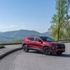 Front 3/4 view of 2024 Chevrolet Trax RS in Crimson Metallic parked on a road with mountains in the background