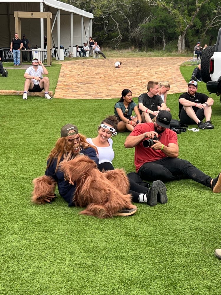 Fans relax on the grass at Ford's Bronco Off-Roadeo Texas Eclipse Event, including someone dressed up as Bigfoot (or perhaps an actual Bigfoot)