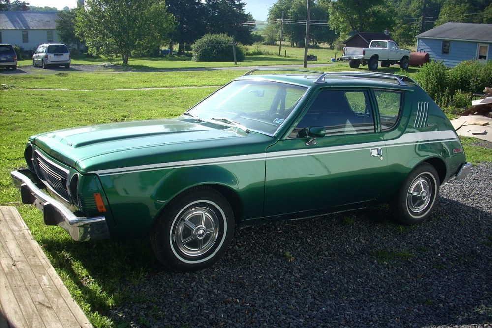A green AMC Gremlin parked in a rural home area