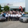 Employees at Subaru of Indiana pose with a 1990 Legacy and a 2020 Legacy