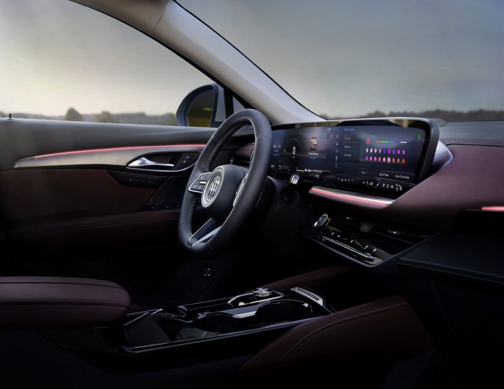 The steering wheel, 30-inch screen, and Garnet upholstery inside the 2024 Buick Envision Sport Touring, shown from the passenger’s seat