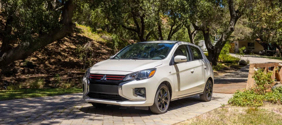 A white 2024 Mitsubishi Mirage is parked in front of a natural backdrop