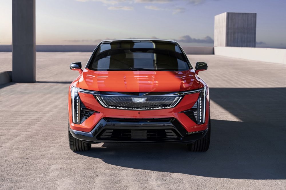 Head-on view of 2025 Cadillac OPTIQ in Monarch Orange, featuring Cadillac vertical lighting signature, sleek LED headlamps and the black crystal shield grille design.