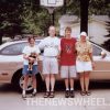 Family standing next to tan Ford Taurus station wagon vehicle