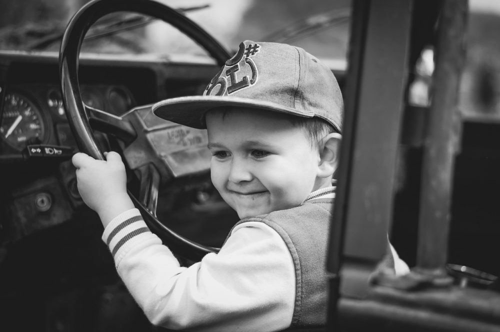 young child boy in driver's seat of car learning to drive