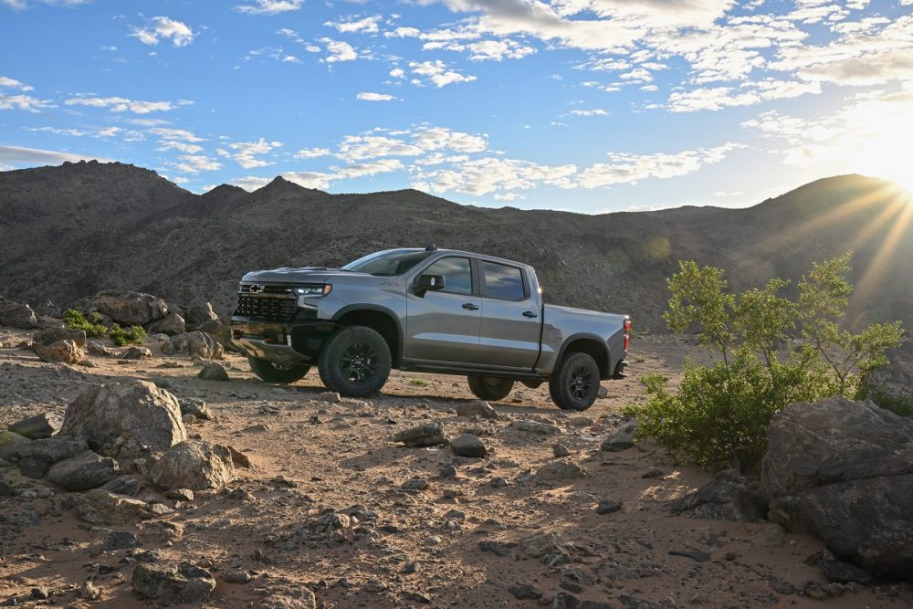 Front three-quarter view of the 2024 Silverado ZR2 on rocky ground with mountains in the background