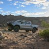 Front three-quarter view of the 2024 Silverado ZR2 on rocky ground with mountains in the background