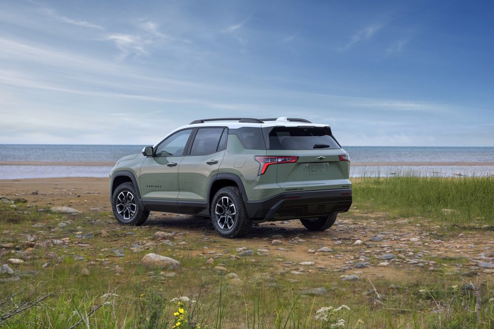 Rear 3/4 view of a 2025 Chevrolet Equinox ACTIV in Cacti Green parked in front of a lake