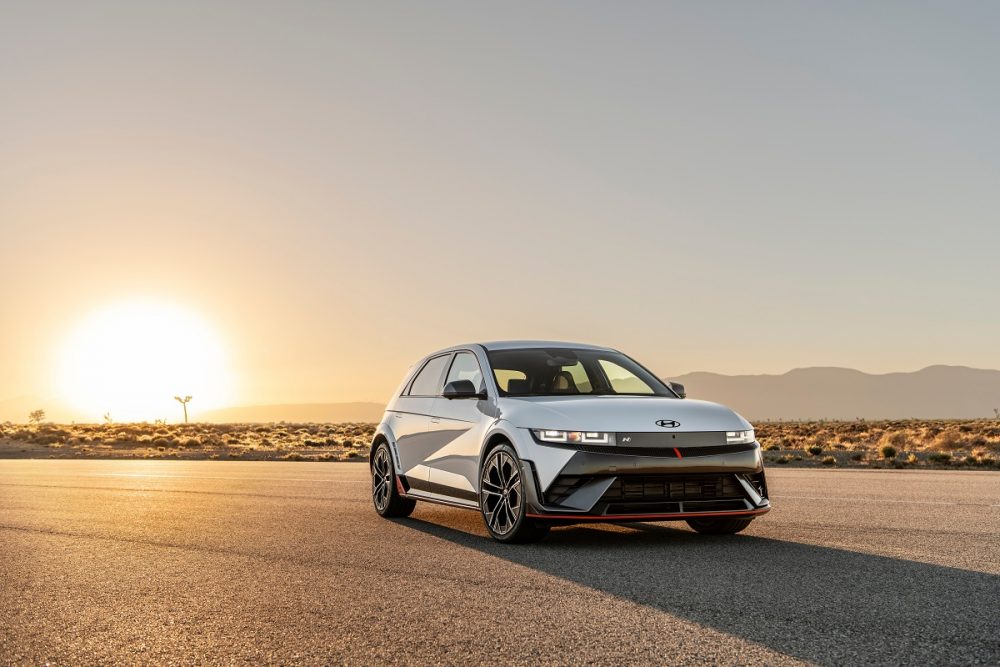 A front side view of the 2025 Hyundai IONIQ 5 N. Behind it, the sun is on the horizon, casting the vehicle's shadow in front of it