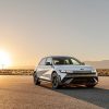 A front side view of the 2025 Hyundai IONIQ 5 N. Behind it, the sun is on the horizon, casting the vehicle's shadow in front of it