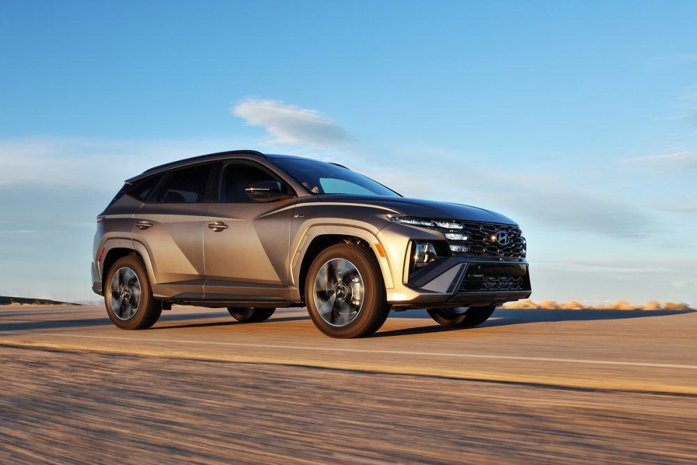 A front side view of the 2025 Hyundai Tucson driving down a road with blue sky in the background