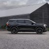 A next-generation 2025 GMC Terrain Elevation with a gray two-tone roof is shown in side profile in front of a barn