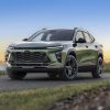 Front 3/4 view of 2025 Chevrolet Trax ACTIV in Cacti Green parked on a road in front of a lake. Pre-production model shown. Actual production model may vary.