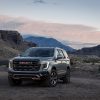 Front 3/4 view of the 2025 GMC Yukon AT4 Ultimate against a rocky backdrop at sunset