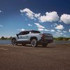 A rear 3/4 view of a Slate Gray 2025 Chevrolet Silverado EV LT parked under a blue sky with fluffy white clouds