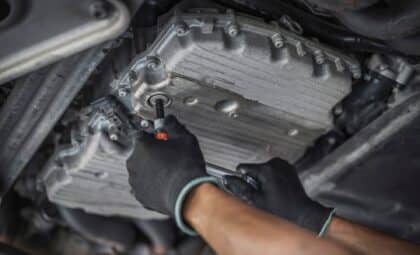 Auto mechanic tightening an oil drain plug