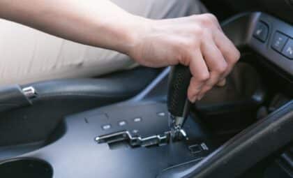The driver holds onto the automatic transmission shift lever