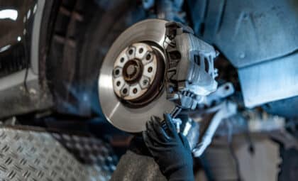 Close-up of mechanic's hands wearing gloves inspecting car brake disc