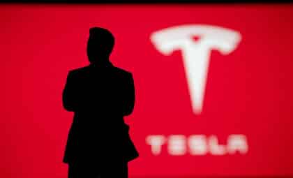 Silhouette of Elon Musk on Tesla presentation, company logo on red background